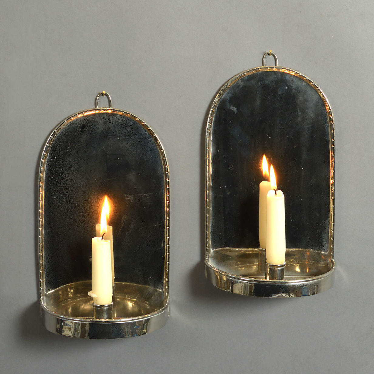 A pair of silver plated wall lights in the queen anne manner