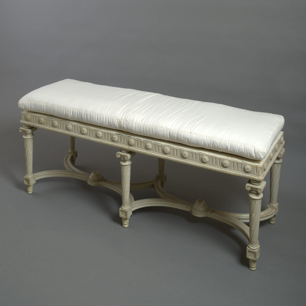 A late 19th century white painted long stool in the louis xvi manner