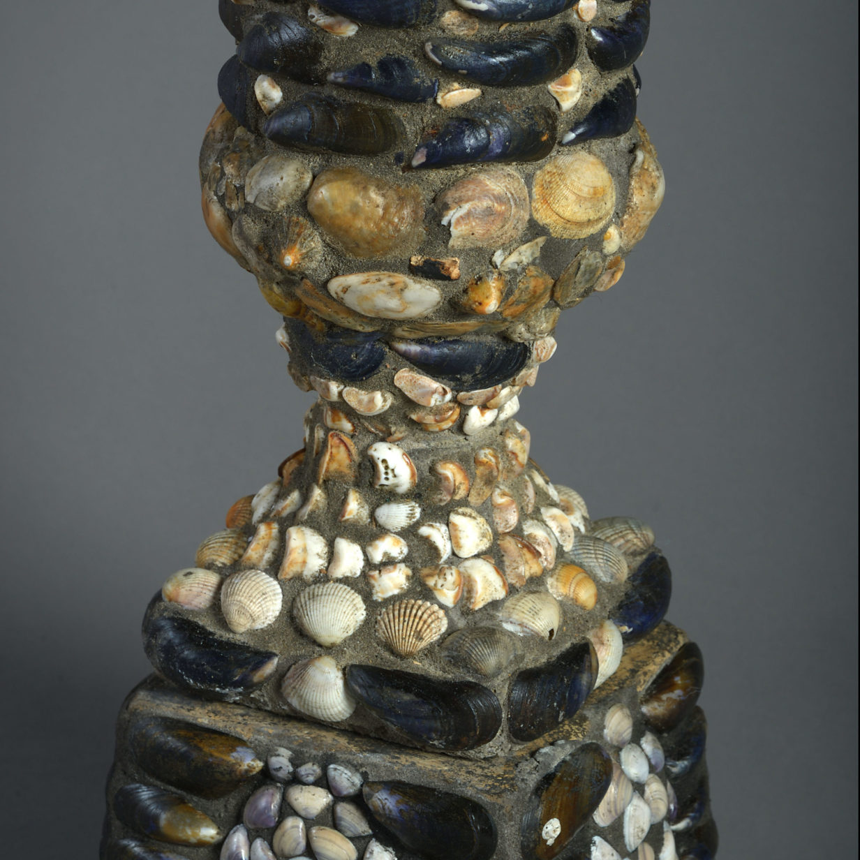 A large pair of shell encrusted urns on plinths