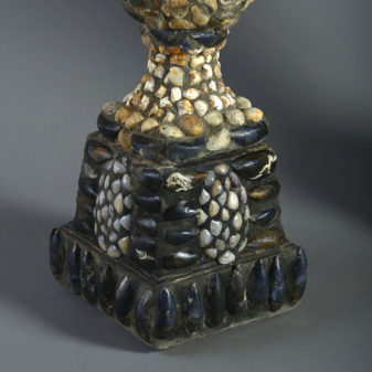 A large pair of shell encrusted urns on plinths