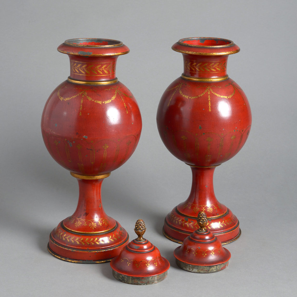 A pair of red toleware late 19th century covered urns