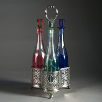 A 19th century silvered bottle carrier and three coloured glass cordial bottles with a silvered carrier