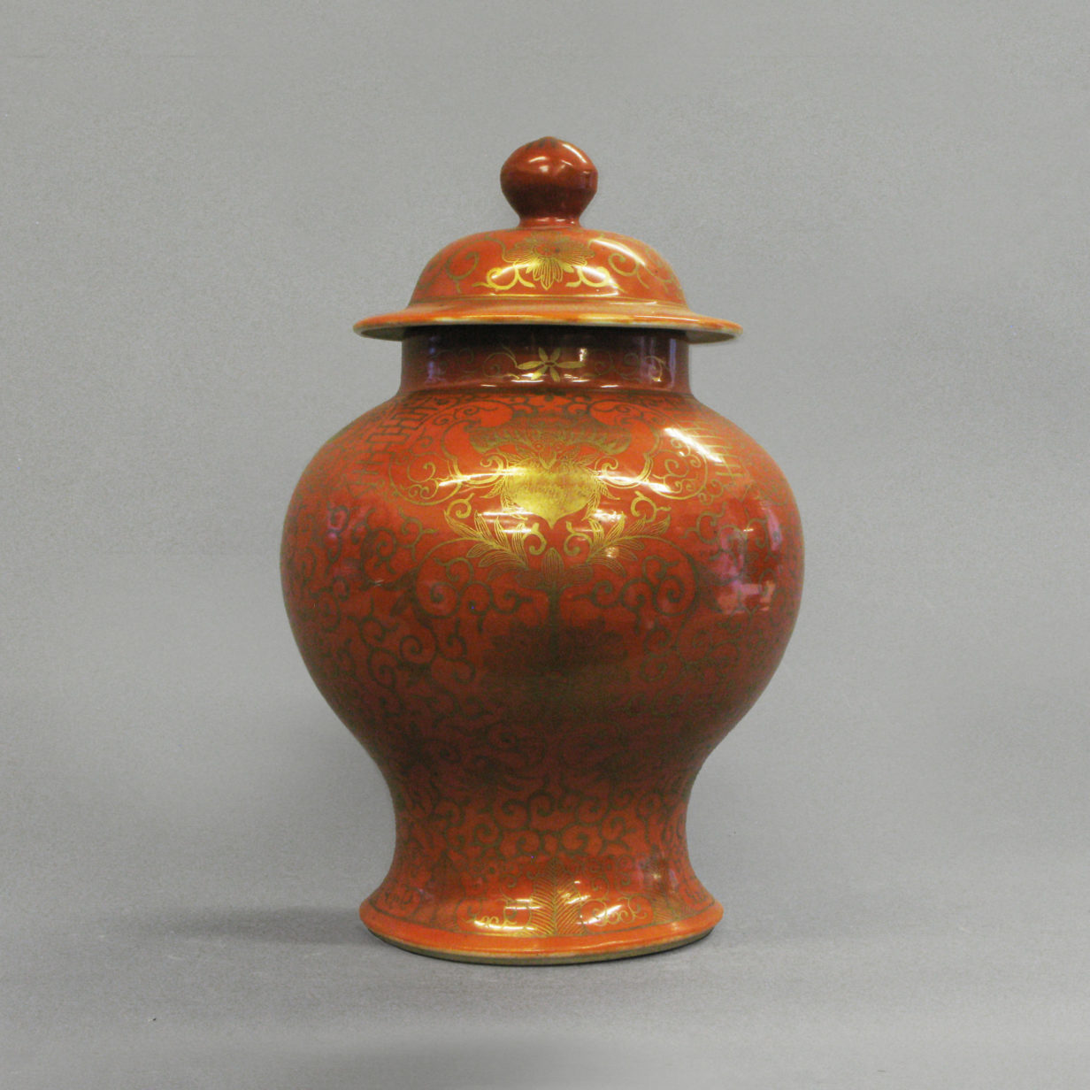 An orange glazed and gilt vase with cover