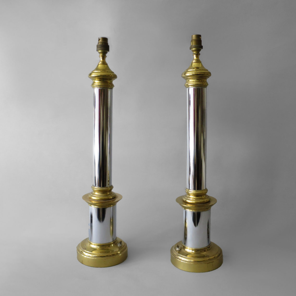 A pair of chrome and brass column lamps
