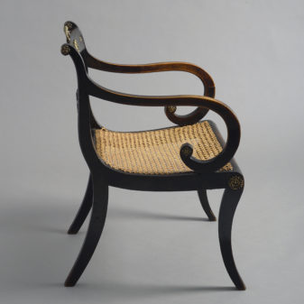 An early 19th century regency period ebonised armchair
